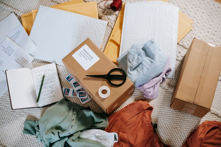 From above of various carton boxes and labels near clothes on surface in room