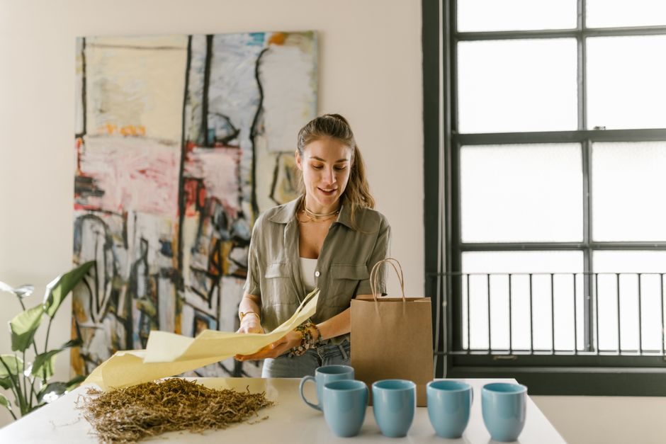 A woman organizing cups and packaging materials in a stylish, bright room.